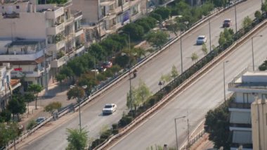 Yaz aylarında hareketli arabalar ve modern binalar ile Atina karayolları havadan çekim yoğun trafik ve yaz güneşli bir günde çevrelerinde ağaçlar ile çok katlı konut ve idari evler ile Atina karayolu harika görünümü