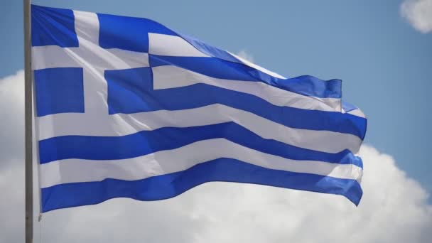 クロスとストライプが高い旗柱の上に飛ぶ1つのギリシャの旗は スロモの晴れた日に白と青のストライプでセレステの空に飛んで十字架と青と白のストライプを持つ大きなギリシャの旗のエキサイティングな眺め — ストック動画