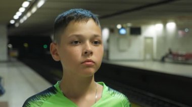 Yazın Atina yeraltı sisteminde metro istasyonunda bekleyen küçük bir çocuk, Atina 'daki bir metro istasyonunda, 11 yaşında, ayakta duran ve metro trenini bekleyen küçük bir çocuğun heyacanlı portresi. Sanatsal ve orijinal görünüyor..