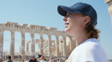 Güneşli bir yaz gününde, şapkalı neşeli sarışın bir kadının güneşli bir yaz gününde zarif ve antik Akropolis 'e bakışını görmek etkileyici. Güzel ve güzel görünüyor..