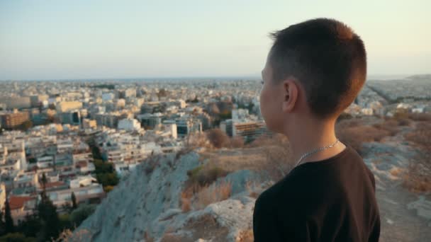 Χαρούμενο Αγόρι Στέκεται Πάνω Από Ένα Λόφο Και Κοιτάζοντας Αστικό — Αρχείο Βίντεο