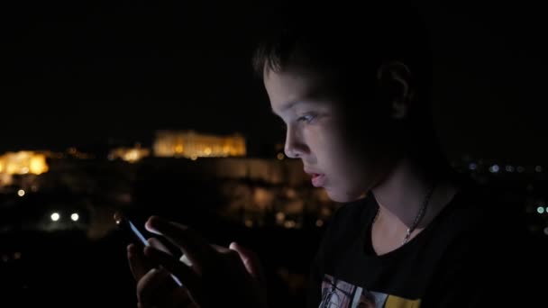 Kleiner Junge Der Abends Der Stadt Steht Und Videospiele Spielt — Stockvideo