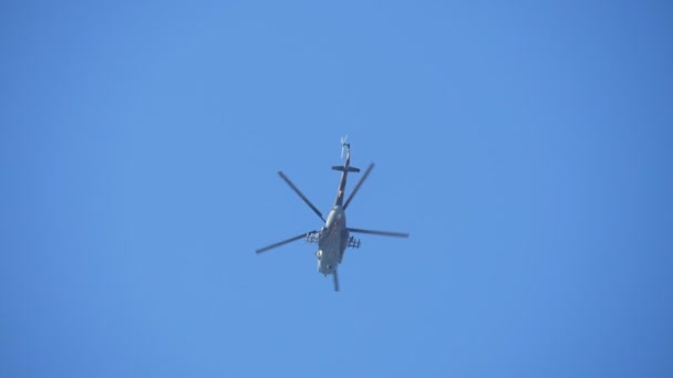 Copter de l'armée et un parachutiste en vol stationnaire dans l'air bleu en automne au ralenti Vue imprenable vers le bas de gros giravion militaire vert et blanc planant dans le ciel bleu et un parachutiste militaire en vol stationnaire en automne au ralenti . 