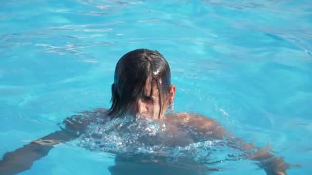 在游泳池水域里 一只喜气洋洋的家伙在慢动作中闭上眼睛 看着一个开朗的年轻布鲁内特男子从水里出来 闭着眼睛 在游泳池里 以慢动作的塞莱斯特水域 他感觉很好 — 图库视频影像