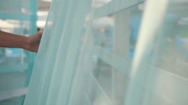 İhale el yavaş hareket yavaş hareket te güneşli bir günde bir deniz beldesinde ahşap bir gölgelik kapsayan mavi bir voile dokunarak güzel bir makyaj ile bir kadın elin slo-mo Wonderful görünümünde yaz aylarında hafif bir gölgelik kapsayan mavi bir voile dokunmadan