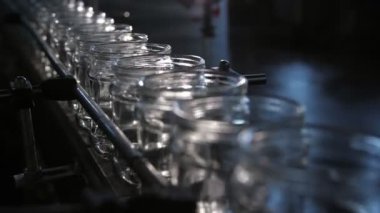 Domates işleme fabrikasındaki bir konveyör şeridinde yuvarlanan havadar cam bankalar modern domates üretim tesisinin geniş bir koridorunda içi boş cam kavanozların itiş kakış görüntüsü. Son derece teknolojik ve iyi görünüyor..
