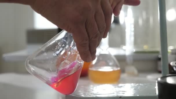 Αρσενικά Χέρια Ανακινούν Μια Εργαστηριακή Τριγωνική Φιάλη Ροζ Υγρό Ευάερο — Αρχείο Βίντεο