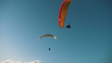 Yazın güneşli bir günde renkli paraşütlerle uçan iki cesur paraşütçü güneşli bir yaz gününde renkli paraşütlerde süzülen iki cesur paraşütçünün görüntüsüne ilham veriyor. Çok güzel ve muhteşem görünüyor..