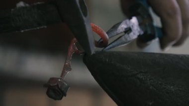 Demirci atölyesindeki maşalarla vurulan eski bir metalik gül, tek yapraklı harika bir retro gülün yakından çekimi, demirci atölyesinde çekle vurularak tutulur. Sanatsal, neşeli ve romantik görünüyor..