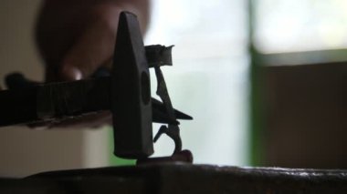 Erkek eller, bir atölyede örsün üzerinde güzel bir gül yapıp vuruyor ve demirci atölyesindeki bir örsün üzerinde ince yapraklarla erkek ellerine vuruyor ve yumuşak bir gül yapıyor. Eski ve iyi görünüyor..