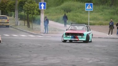 Zaporizhia, Ukrayna - 18 Mayıs 2020: Güneşli bir yaz gününde, yavaş çekimde, geniş bir motosiklet pistinde iki kişinin kayarak ve dans ederek halka kaydığı spor bir arabanın görüntüsü