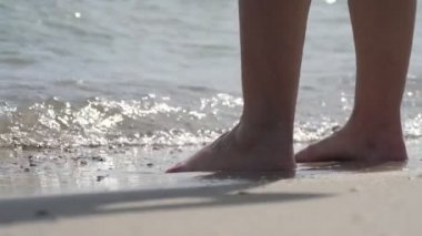 Yazın güneşli bir günde köpüklü deniz sularında ayakta duran erkek ayakları yavaş çekimde Karadeniz 'in köpüklü ve dalgalı sularında ağır çekimde duran erkek bacaklarının yakınlaşmasını sağlar. İyi görünüyor..