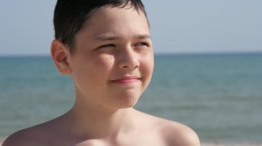 Şanslı çocuk Karadeniz kıyısında duruyor ve yazın ağır çekimde gülümsüyor. Yazın güneşli bir günde Karadeniz kıyısında durup gülümseyen mutlu bir çocuğun heyacanlı görüntüsü. Deniz manzarası harika ve ilham verici görünüyor..