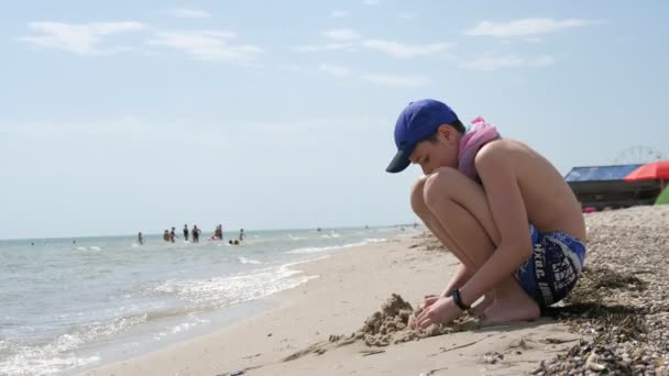 Ragazzo Allegro Berretto Pantaloncini Seduto Giocare Con Sabbia Sulla Costa — Video Stock