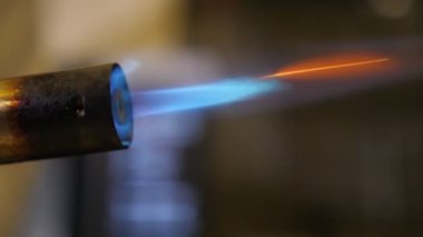 Geniş bir atölyede mavi yangın akışıyla alev alan gaz kaynak makinesi, geniş bir atölyedeki silindirik metalik bir başlıktan fışkıran mavi ve turuncu bir ateş akışı ile tutuşan gaz kaynaklama makinesinin etkileyici bir yan görüntüsü..