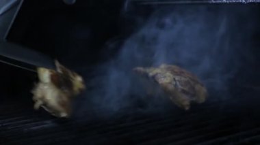 Biftek kaburgaları fırında pişirilir ve uzun metal maşalarla baş aşağı yerleştirilir. Siyah bir fırında ızgara edilmiş biftek kaburgalarının ilham verici görüntüsü ve uzun metal maşayla ters çevrilmiş olarak yerleştirilir. Az pişmişe benziyorlar, çok lezzetli..