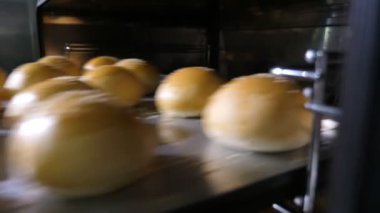 Elleri siyah eldivenlerle bir restoranın mutfağında yuvarlak çöreklerle tepsileri alırken siyah eldivenli ellerin bir restoranın mutfağındaki metal tepsilere altın yuvarlak çörekler koyması etkileyici. Taze, güzel ve lezzetli görünüyorlar..