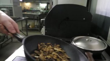 Aşçının elleri mutfakta yavaş çekimde mantar pişirir ve kusar. Şefin ellerinin kustuğu ve mantarları bir restoranın mutfağında yavaş çekimde pişirirken karıştırdığı etkileyici bir yakın plan. Güzel ve komik görünüyor.