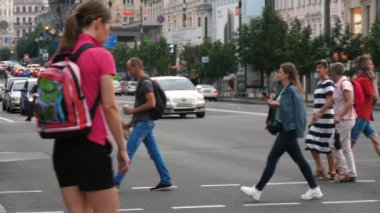 Kiev, Ukrayna-29 Haziran 2020: Yavaş çekimde güneşli bir yaz gününde yoğun bir caddeden geçen kot ve tişörtlü bir düzine genç ve zarif insanın etkileyici görüntüsü. .