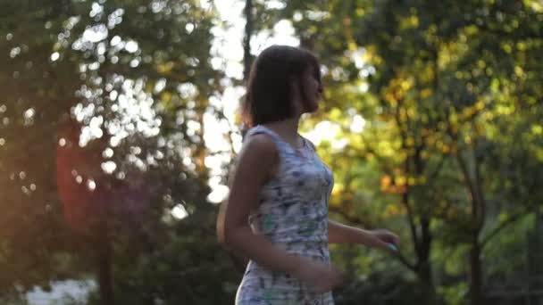 幸せなブルネットの女の子は振り向いて 夏に公園でスロ Moでスマートになります陽気なブルネットの女の子の素晴らしい景色笑顔 振り向いて 彼女の髪を順番に 緑の公園でゆっくりとした動きで日没を輝いて — ストック動画