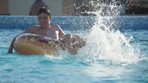 Vermakelijke Jongen Spetterend Water Met Zijn Voeten Een Waden Zwembad — Stockvideo