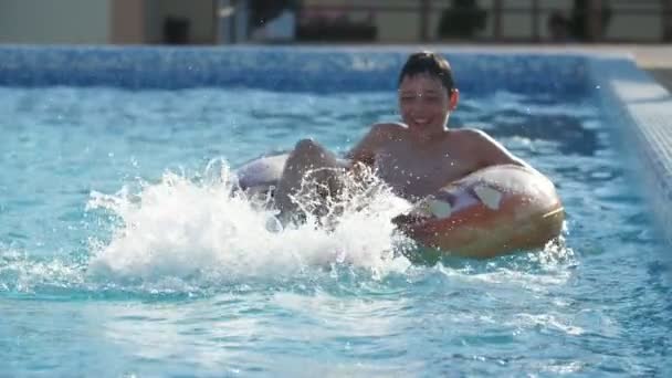 Glad Pojke Stänk Vatten Med Fötterna Glänsande Pool Slow Motion — Stockvideo