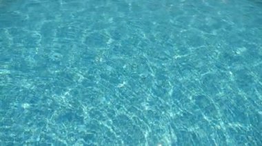 Celeste dalgaları sakin bir şekilde yüzme havuzunda sallanıyor yazın bir deniz tatil köyünde şeffaf mavi suların sakin bir şekilde sallanışının ve güneşli bir yaz günü güneşli bir tatil köyünde güneş ışınlarının yüzeylerine yansımasının heyecan verici arka plan görüntüsü.