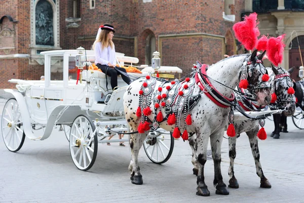 KRAKOW, POLONIA - JUNIO, 2017: Carruaje de caballos tradicional en la plaza principal del mercado de la ciudad vieja. Plaza del Mercado Principal. Fiacre de caballos y gente en el casco antiguo de Cracovia — Foto de Stock