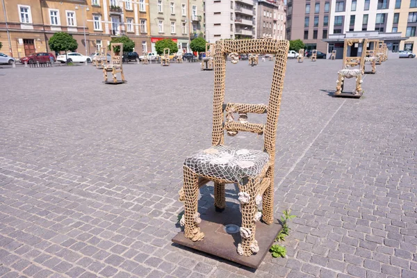 KRAKOW, POLAND - JUNE, 2017: Massive chair on cobblestone street in art installation in memory of Jewish ghetto. Krakow with popul. of 800,000 people has 2.35 mill. foreign tourists annually — Stock Photo, Image