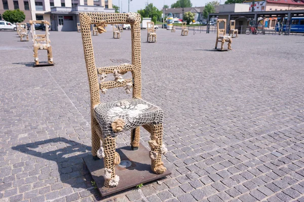 KRAKOW, POLAND - JUNE, 2017: Massive chair on cobblestone street in art installation in memory of Jewish ghetto. Krakow with popul. of 800,000 people has 2.35 mill. foreign tourists annually — Stock Photo, Image