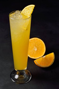 Yüksek bir bardakta buz gibi narenciye kokteyli. Menü için kopyalama alanı ile koyu arka plan.