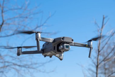 ST. PETERSBURG, RUSSIA - APRIL, 2019: DJI Mavic 2 pro with Hasselblad camera. Flight against blue sky in park clipart