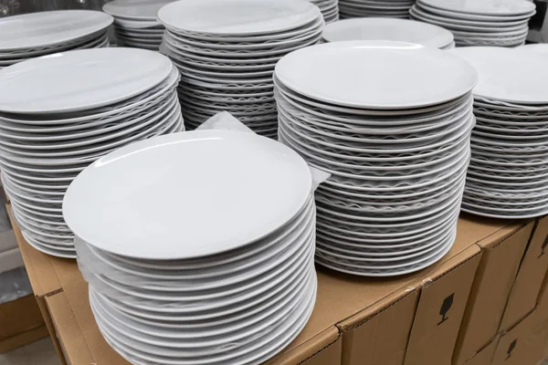 Стопки из многих белых тарелок на полке с проволокой на коммерческой кухне — стоковое фото
