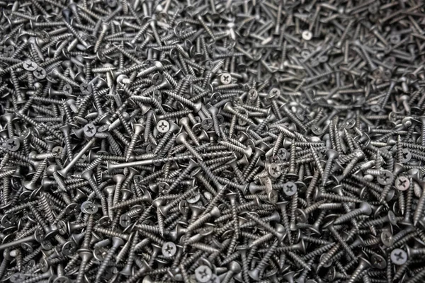 Metal fasteners. Many black tapping screws for construction as an industrial style background, close-up.