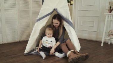 Teepee beyaz çadır kreş ve annesiyle oynayan küçük bir kız