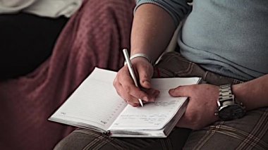 bir adam insan bir not defterinde yazıyor