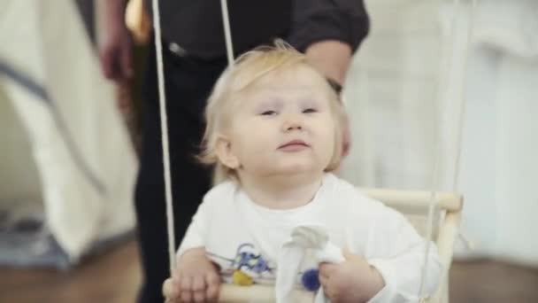 Маленькая девочка качается на качелях улыбаясь — стоковое видео