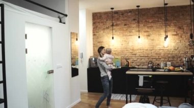 Genç anne, bebeğe sarılan küçük kızıyla oynuyor.