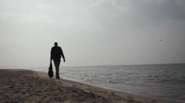 20 yaşındaki genç adam elinde bir sırt çantasıyla Baltık Denizi kıyısında yürüyor. 