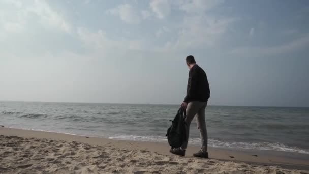 Jongeman 20 jaar oud loopt langs de kust van de Oostzee met een rugzak in zijn hand — Stockvideo