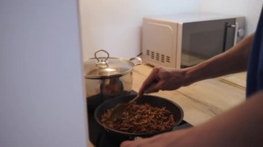 mutfakta spagetti bolonez patates bir tavada sos ile kıyma pişirme genç adam