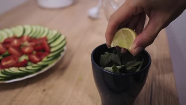 Mojito-Cocktail zubereiten, Limettensaft in ein Glas mit Minze und Eis pressen — Stockvideo