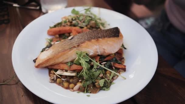 Жареный лосось стейк с овощами на тарелке в ресторане — стоковое видео