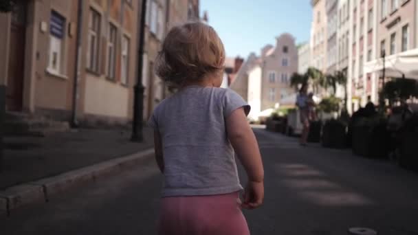 Kleine krullend blond meisje reist wandelen door de straat — Stockvideo