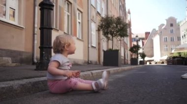 sokakta yürürken yolda oturan küçük kıvırcık sarışın kız