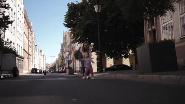 Jovem feliz mãe corre atrás de uma criança por uma menina na rua pegando — Vídeo de Stock