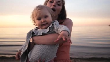 Anne ve kızı gün batımı gülüyor deniz kıyısında yürümek 