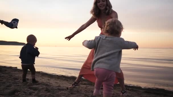 Fiatal anyák a tengerparton a gyermekekkel a Balti-tenger naplementekor játszott — Stock videók