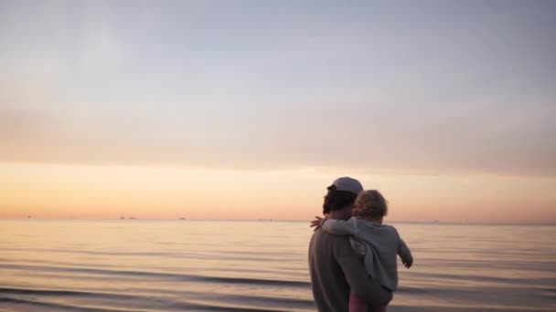 Joven padre juega con pequeña hija en la playa abrazos y risas, vomita — Vídeos de Stock
