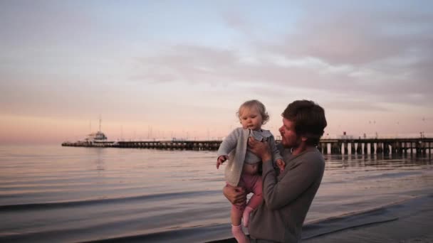 Mladý otec hraje s malou dcerou na pláži, v objetí a smíchu, hází — Stock video